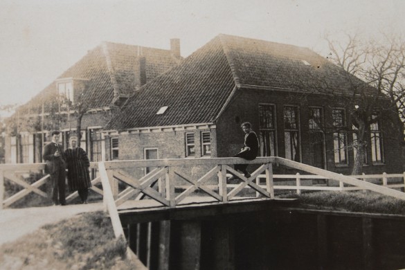 Het oude schoolgebouw. Op de brug staan meester Ravenhorst met zijn vrouw, op de leuning...